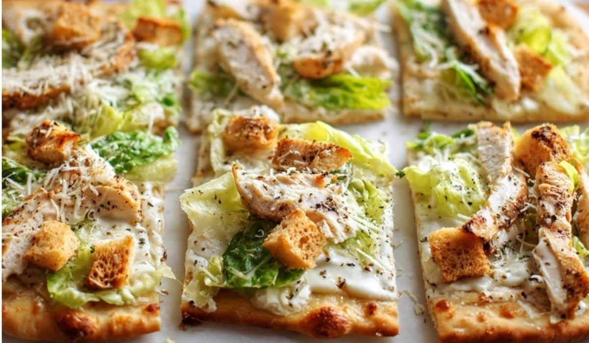 Chicken Caesar Flatbread cut into squares topped with grilled chicken, romaine, croutons, and creamy Caesar dressing