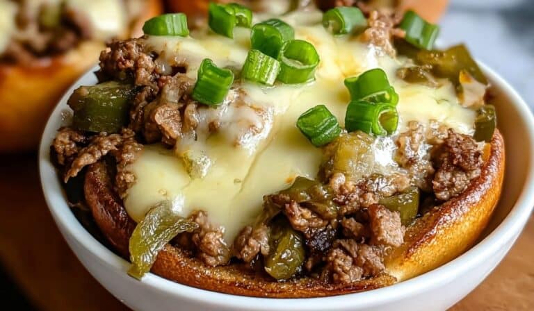 Philly Cheesesteak Bowls with ground beef, peppers, melted cheese, and scallions served in a bread bowl