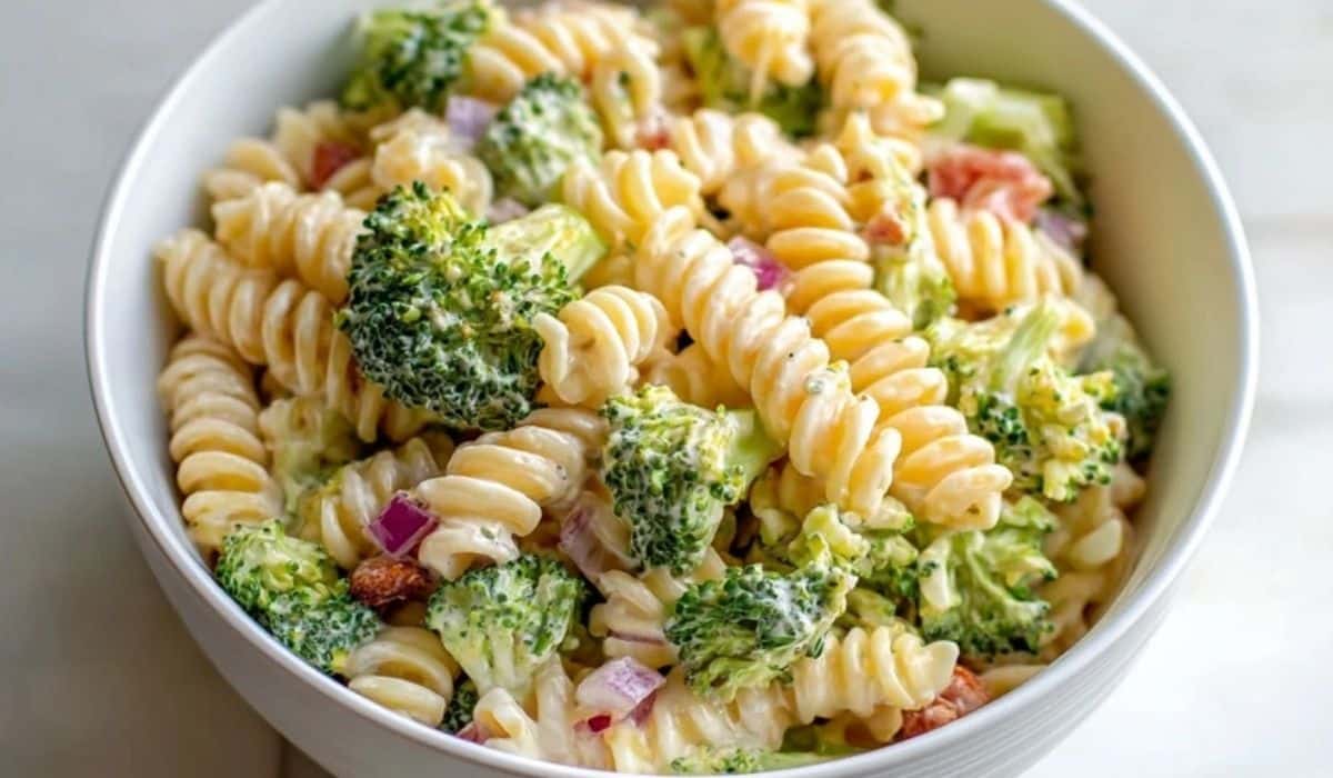 Broccoli Pasta Salad with rotini, red onion, and creamy dressing in a white bowl