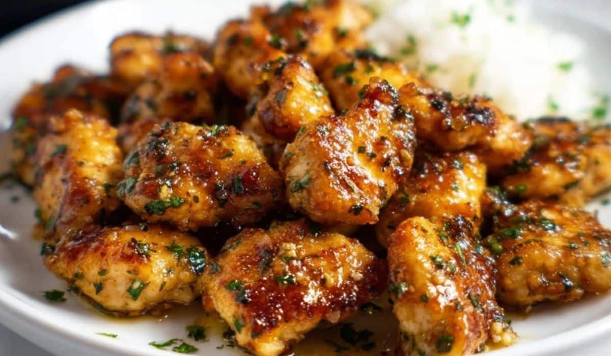 Alt Text: Garlic Butter Chicken Bites with herbs and a side of rice on white plate