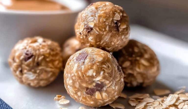 Peanut butter oat energy bites stacked on white surface with oats