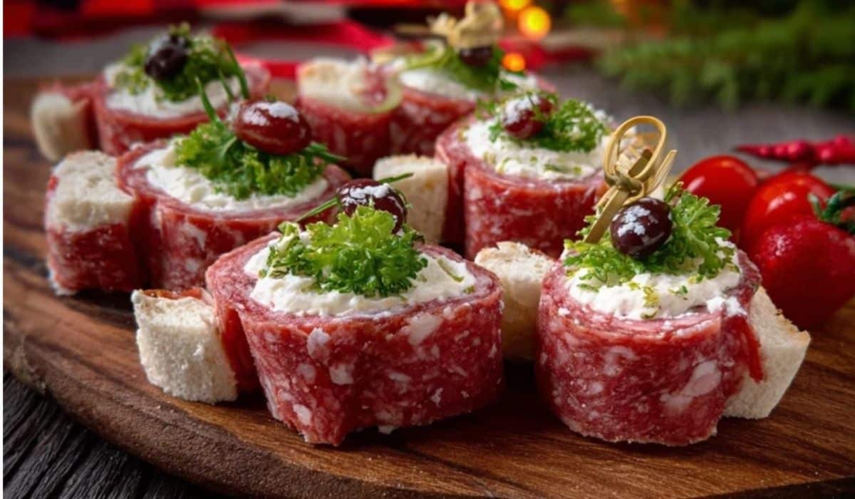 Smoky salami cream cheese roll-ups with herbs and cranberries on wood board