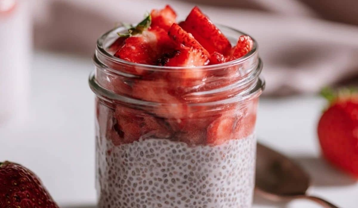 Strawberry Chia Seed Pudding with Coconut Milk in a clear jar topped with diced fresh strawberries