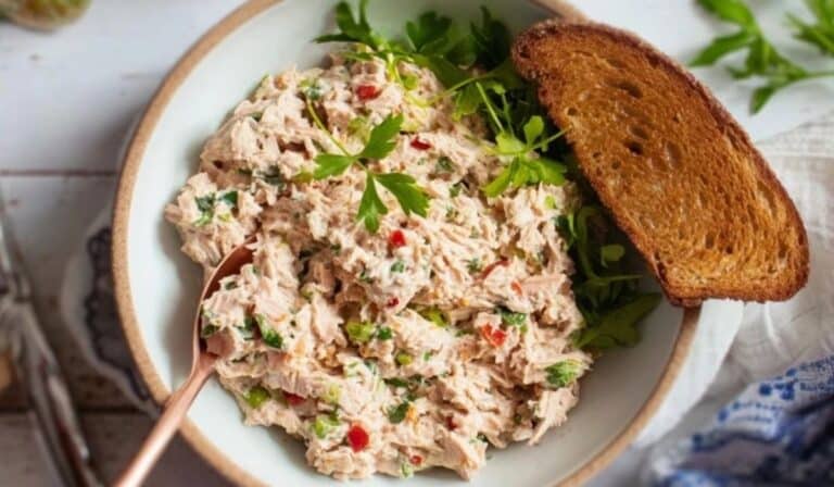 Tuna Salad in a white bowl with toasted bread and herbs