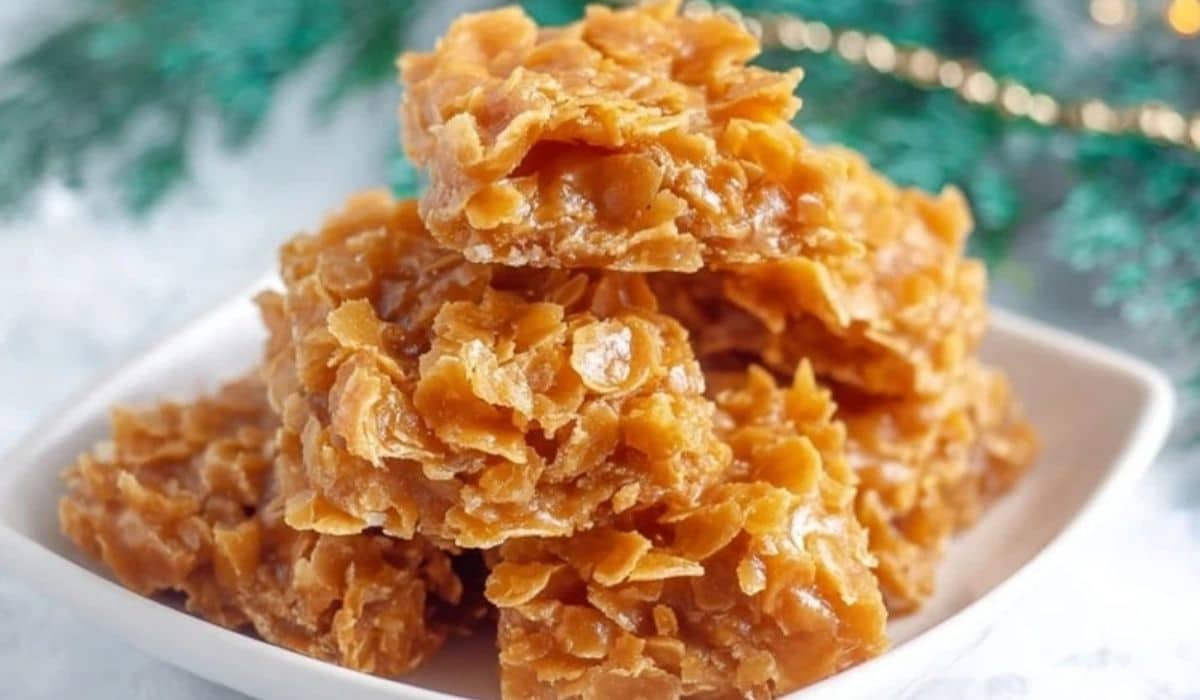 Cornflake Candy stacked on a white plate with holiday decorations in the background