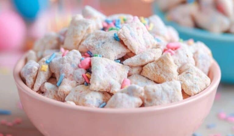 Birthday Cake Puppy Chow Recipe in pink bowl topped with colorful sprinkles