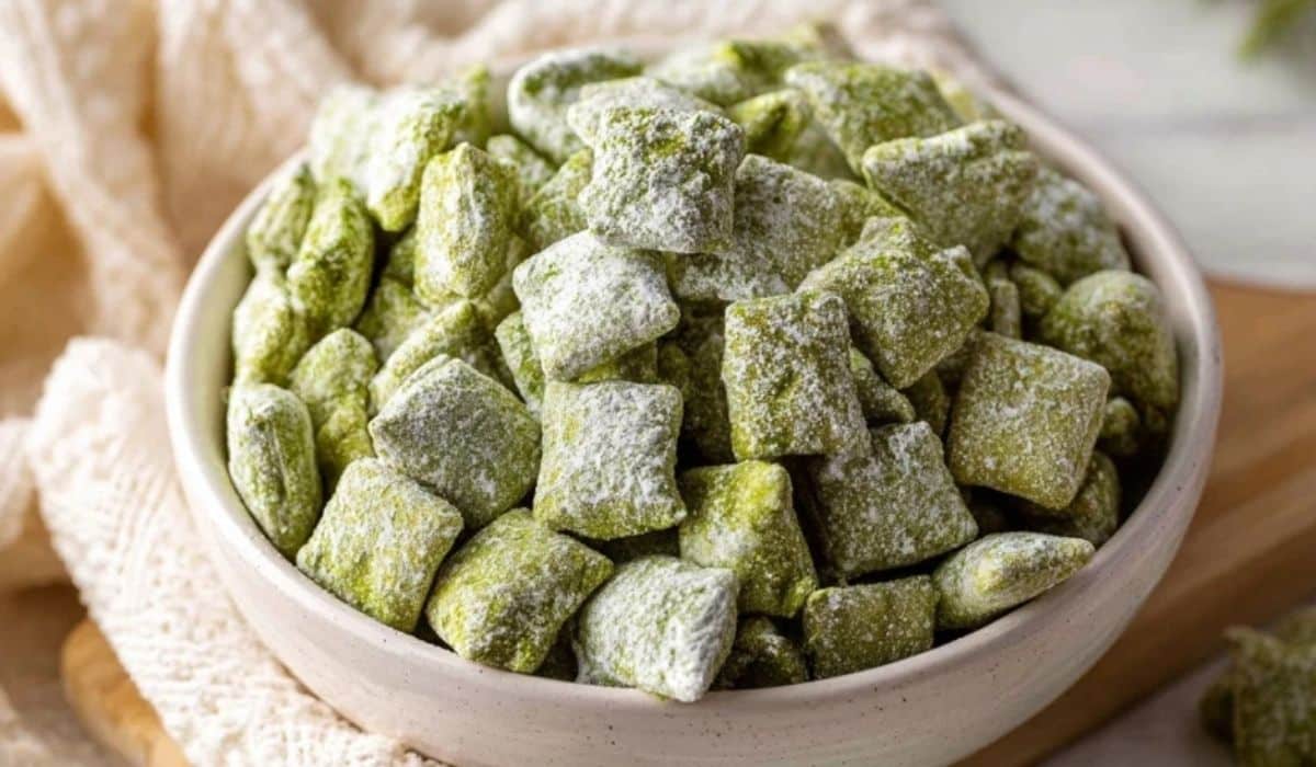Matcha Puppy Chow in a white bowl coated with powdered sugar