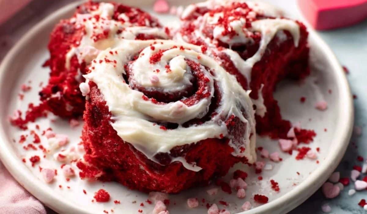 Red Velvet Valentine's Day Cinnamon Rolls on a serving plate with cream cheese frosting