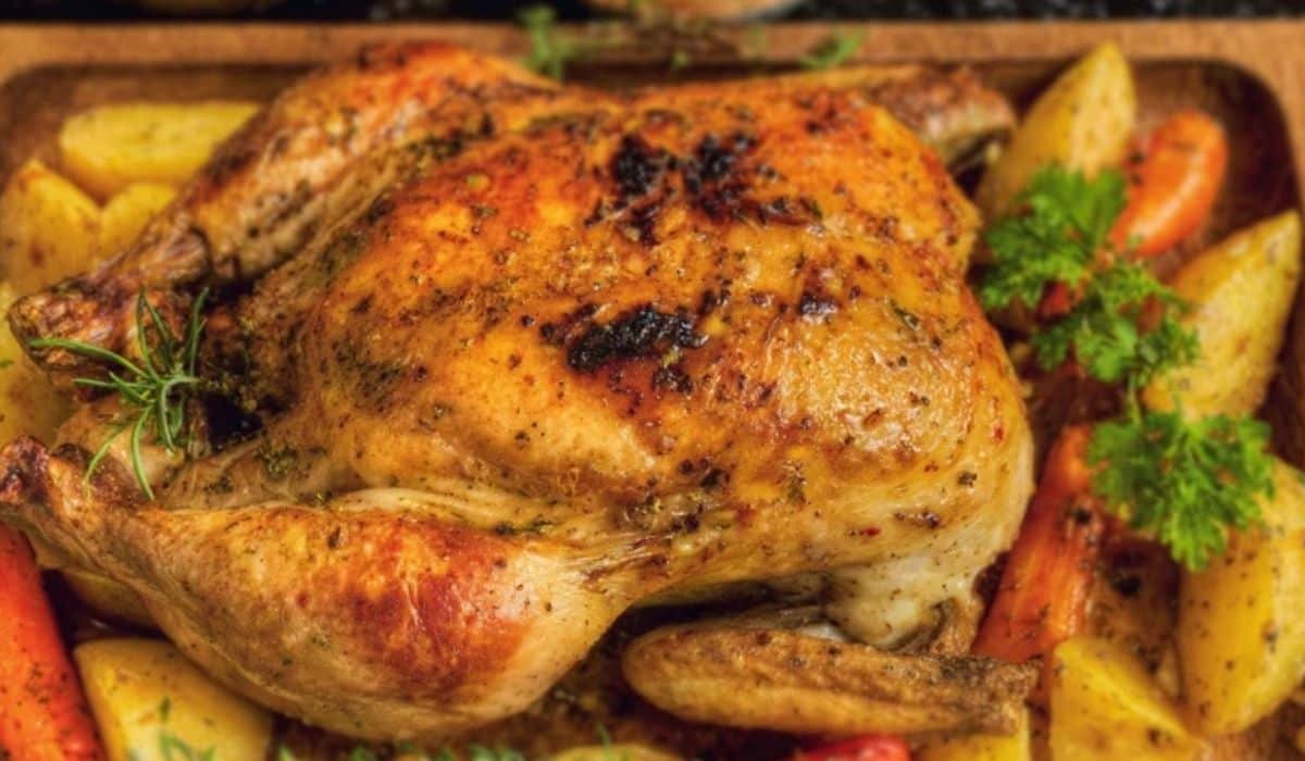 Moist roasted whole chicken with crispy golden skin and vegetables in pan
