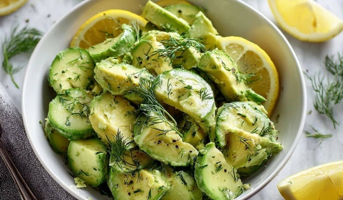 Cucumber avocado lemon salad in a white bowl with fresh dill and lemon slices