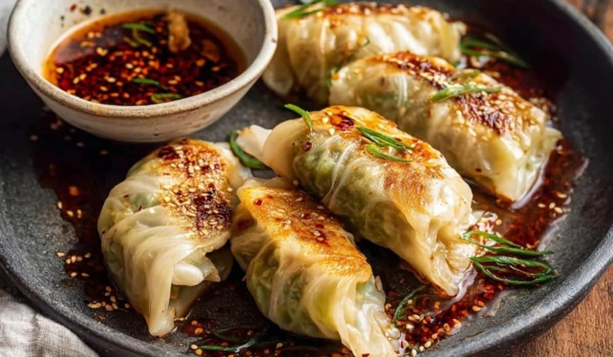 Korean-style cabbage rolls with chili oil on a platter with sesame and scallions