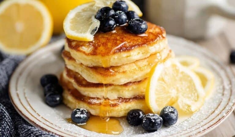 Fluffy lemon ricotta pancakes stacked high with syrup and berries