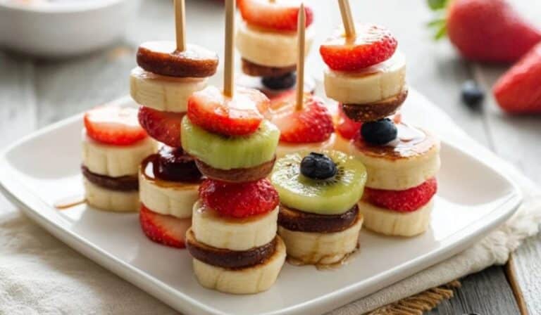 Mini pancake skewers with fruit on a brunch platter with maple syrup