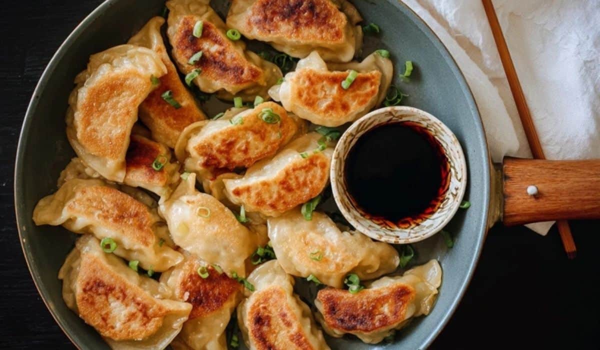 Pan-fried cabbage dumplings in a skillet with dipping sauce