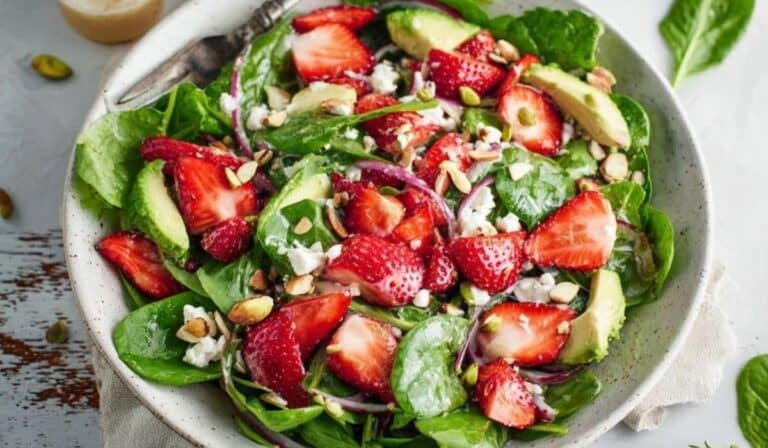 Strawberry spinach spring salad in a large bowl with berries, avocado and nuts